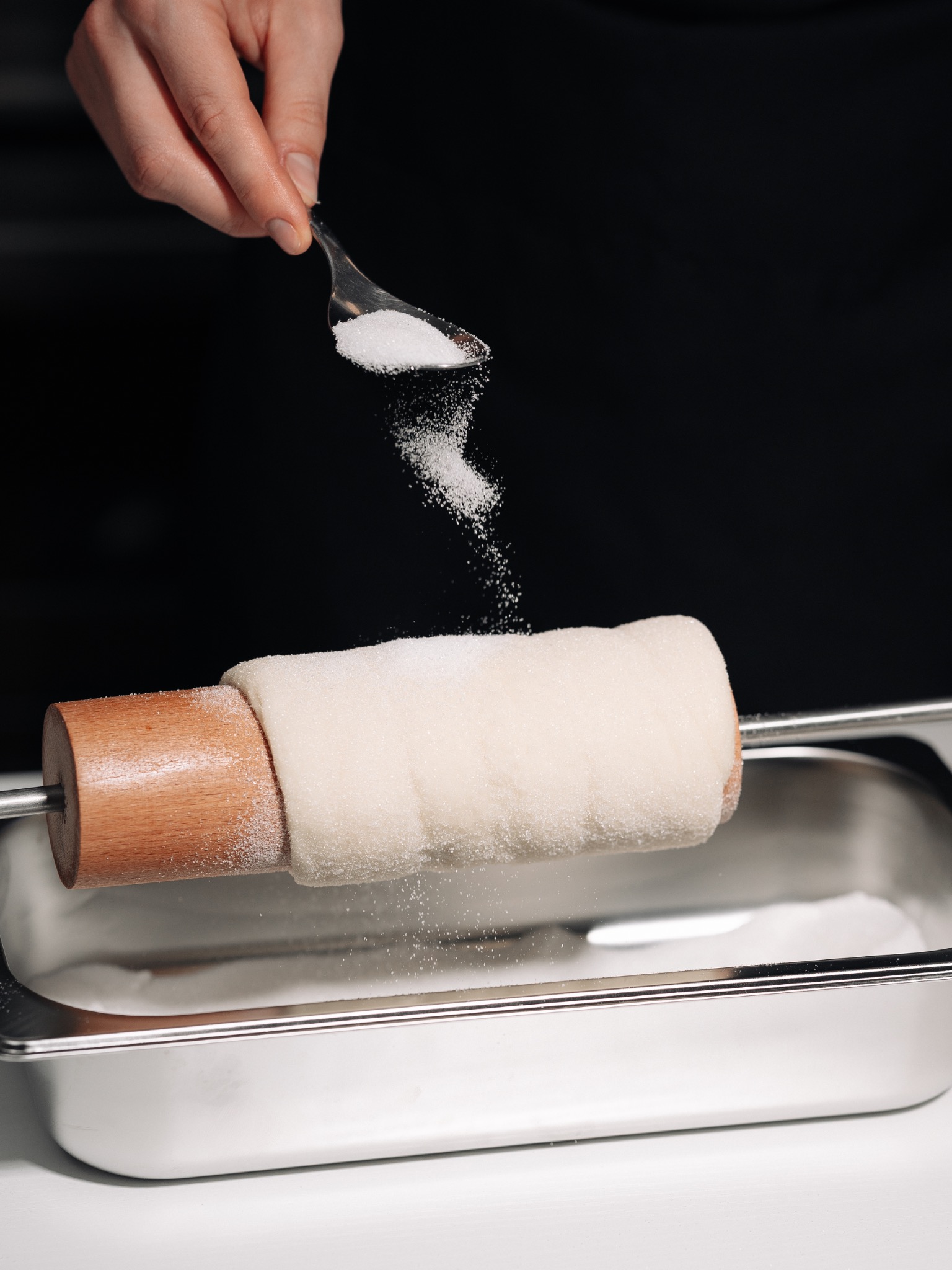 Sugar being sprinkled on fresh chimney cake dough